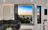 Floor-to-ceiling sliding glass doors, glass balcony railing, recessed lighting, and white stone-finish flooring with water horizon backdrop