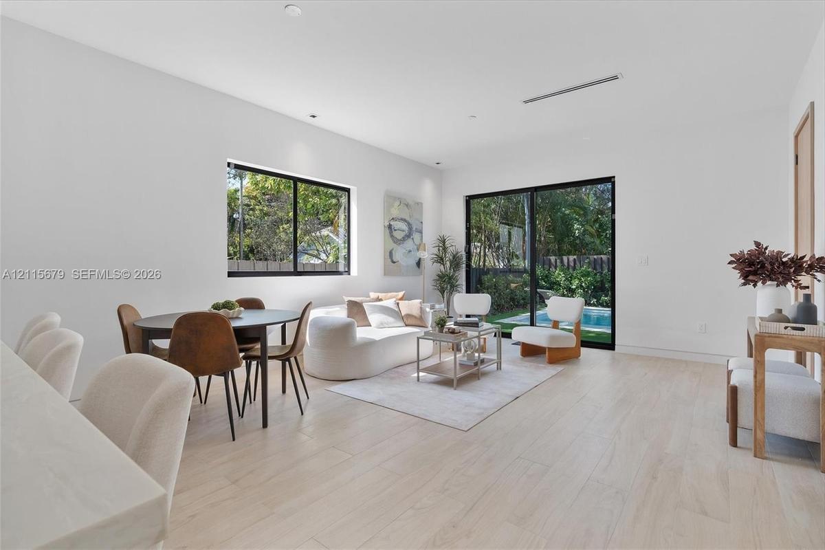 Living area featuring light-toned wood-finish flooring, sliding glass doors, recessed lighting, and a square window