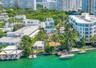 Waterfront estate featuring private boat docks, paved exterior decking, mature landscaping, and multi-level structural design