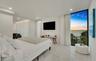 Floor-to-ceiling black-framed windows, large-format stone-finish flooring, recessed lighting, cove lighting, and water backdrop