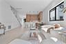 Open-concept interior featuring light wood-finish flooring, custom wood-veneer cabinetry, a center island with bar seating, and a glass-paneled stairc