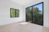 Neutral interior space featuring wood-finish flooring, floor-to-ceiling sliding glass doors, a secondary window, and matte black framing