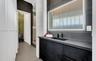 Modern vanity featuring dark cabinetry, a solid-surface countertop, an integrated rectangular sink, and a wall-mounted faucet, accented by a backlit m