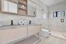Floating vanity with integrated sinks, wood-finish cabinetry, matte black faucets, and full-height stone wall tile
