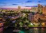 Waterfront property featuring deep-water boat slips, private docks, and tropical landscaping situated against a city skyline backdrop