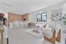 Open-concept living space featuring wood-finish cabinetry, a large kitchen island with quartz-surface countertops, light-toned wood-finish flooring, a