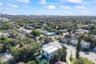 Aerial perspective of a two-story residence featuring a flat roof, white exterior, integrated swimming pool, and mature perimeter landscaping