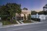 Modern two-story exterior featuring a smooth stucco finish, dark metal louvered privacy screens, expansive glass sliding doors, multiple balconies, an