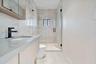Bathroom featuring a wood-finish floating vanity, matte black faucet, full-height tile shower enclosure with a glass door, and large-format tile floor