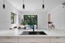Kitchen featuring a stone-surface island, undermount stainless steel sink, matte black faucet, and three modern pendant lights