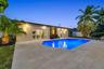 Outdoor space featuring a swimming pool, large-format paver patio, double French doors, and exterior wall-mounted accent lighting