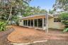 Stucco exterior featuring a covered patio, brick-paver hardscaping, decorative wrought iron support column, and floor-to-ceiling glass panel sliding d