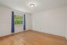 Wood-finish flooring, neutral wall tones, and single-pane window with natural exterior foliage