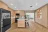 Kitchen featuring light wood-finish cabinetry, herringbone-patterned wood flooring, a central island with an integrated sink and under-counter lightin