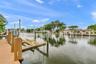 Waterfront property featuring a synthetic wood-finish dock, mechanical boat lift, and bulkhead pilings
