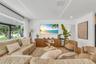 Living area featuring expansive floor-to-ceiling windows, recessed perimeter tray ceiling lighting, and herringbone-pattern wood-finish flooring