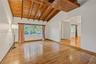Vaulted ceiling featuring exposed wood beams, plank wood-finish flooring, and expansive window configuration
