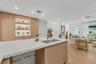 Kitchen featuring light wood-finish cabinetry, a white quartz countertop, an undermount stainless steel sink with a brass faucet, built-in recessed sh