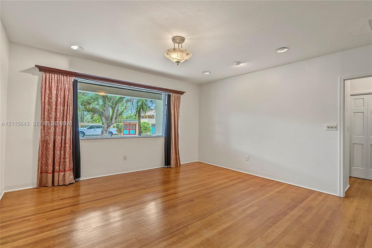 Interior space featuring wood-finish flooring, recessed lighting, a central semi-flush mount light fixture, and a large picture window