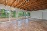 Exposed wood beam ceiling, expansive glass sliding doors, terra-cotta tile flooring, and integrated track lighting
