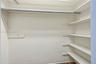 Storage closet featuring a full-width metal clothing rod, upper shelving, and a tiered side shelving system with white-painted finishes