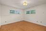 Room featuring wood-finish flooring, two large windows, neutral-toned walls, and a decorative flush-mount ceiling light fixture