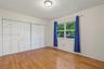 Room featuring wood-finish flooring, white panel-style bi-fold closet doors, a multi-pane window, and a central ceiling-mounted light fixture