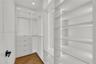 Custom storage system featuring floor-to-ceiling white cabinetry, integrated LED strip lighting, built-in drawer units, adjustable shelving, and herri