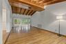 Vaulted ceiling with exposed wood beams, wood-finish flooring, and expansive sliding glass doors opening to a paved patio area
