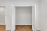White bi-fold closet doors featuring a two-panel design and wood-finish herringbone flooring