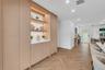 Custom floor-to-ceiling cabinetry featuring integrated LED display shelving, smooth-surface countertops, and light-tone wood finish flooring in a herr