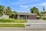 Single-story residence featuring a multi-toned exterior, a natural stone paved driveway, an attached garage, and mature palm landscaping