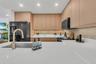 Kitchen featuring flat-panel wood-finish cabinetry, white solid-surface countertops, black integrated appliances, and a brass-tone gooseneck faucet