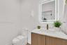 Wood-finish vanity cabinet, white solid-surface countertop, rectangular undermount sink, brass-tone faucet, and rectangular LED-backlit mirror