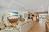 Open-concept living space featuring wood-finish flooring in a herringbone pattern, a recessed rectangular tray ceiling with perimeter lighting, recess