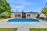 Backyard swimming pool featuring a light-toned stone deck, integrated stair entry, and dual sets of glass-paneled double doors