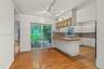 Kitchen featuring wood-finish flooring, white cabinetry with glass-front uppers, wood-tone countertops, patterned tile backsplash, and sliding glass d