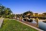 Waterfront property featuring a private wooden dock, boat lift, concrete seawall, and landscaped lawn with mature palm trees