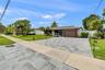 Single-story residence featuring a stone-paver driveway, attached garage with a multi-panel door, and white vinyl perimeter fencing