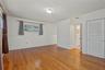 Interior room featuring wood-finish flooring, white walls, and a closet with louvered double doors