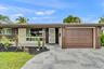 Single-story exterior featuring a stone-paver driveway, integrated garage with a paneled door, covered front entryway, and vertical wood-slat accent s