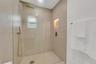Walk-in shower featuring large-format wall tile, a frameless glass enclosure, a rainfall showerhead, a handheld sprayer in a metallic finish, and a re