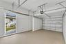 Two-car garage featuring a sectional overhead door, painted concrete flooring, white walls, and a dedicated exterior side-entry door