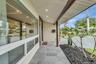 Covered entryway featuring large-format grey stone floor tiles, recessed ceiling lighting, a sprawling paneled window, and dark wood-finish structural