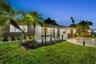 Single-story exterior featuring corrugated metal siding, stucco finish, stone landscape edging, and a paved driveway