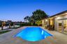 In-ground swimming pool with stone-tiled patio, waterfront bulkhead, and private boat dock