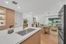 Kitchen island featuring a white countertop and stainless steel undermount sink with a brass-finish faucet, light wood-finish cabinetry, and chevron-p