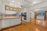 Kitchen featuring wood-finish flooring, butcher block countertops, white cabinetry with glass-front uppers, built-in double wall ovens, and patterned 