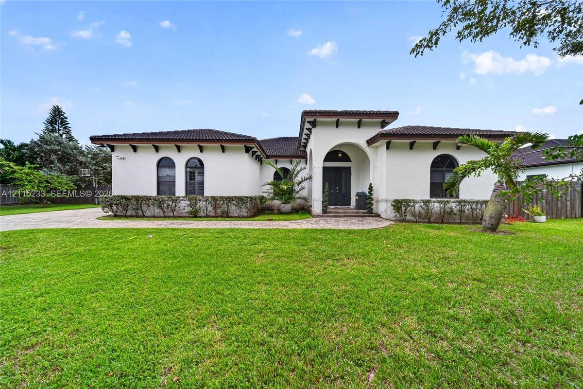 Stucco exterior featuring arched windows, tile roofing, decorative exposed rafters, and a paved walkway