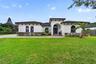 Stucco exterior featuring arched windows, tile roofing, decorative exposed rafters, and a paved walkway